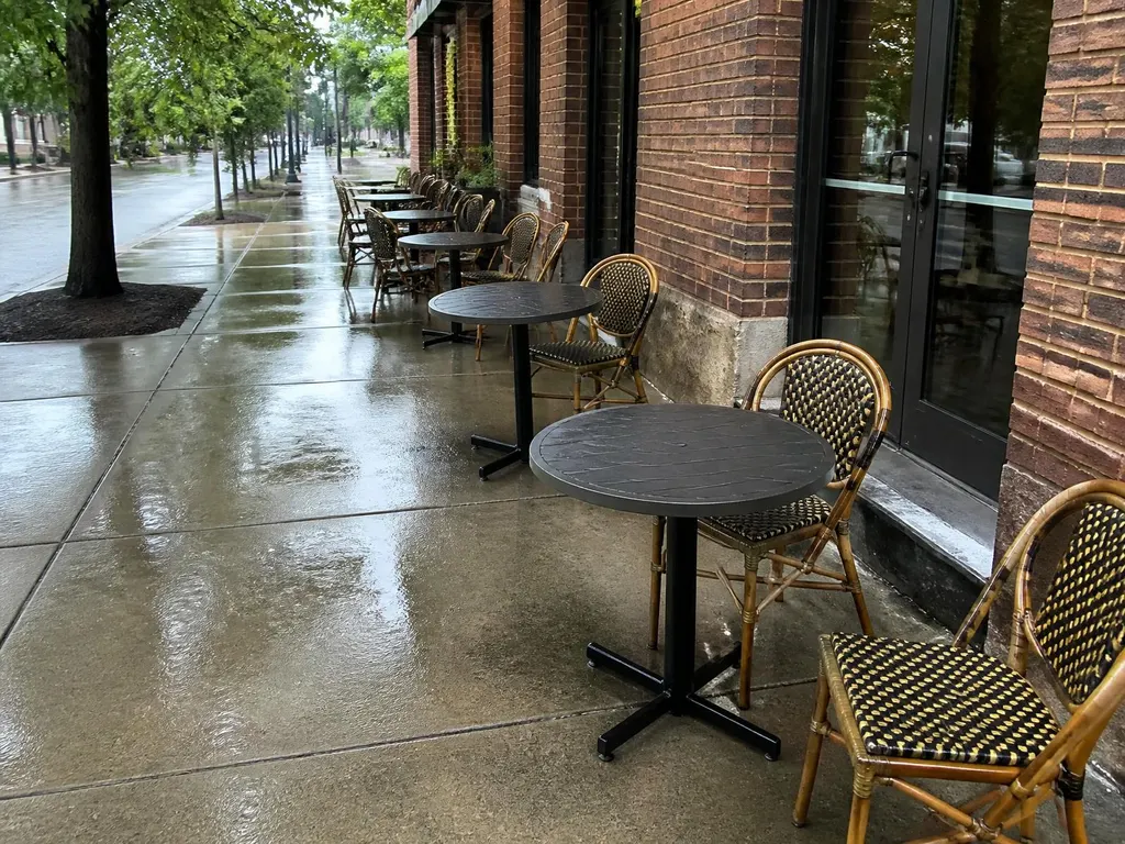Freshly pressure-washed restaurant patio and sidewalk with bistro tables outside a brick building